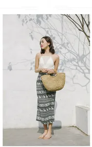 Detail of bohemian long maxi skirt with ethnic elephant prints and a matching straw bag