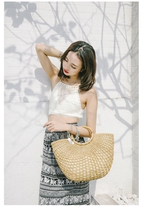 Detail of handmade woven straw beach bag with semi-circle hollow design and round handle