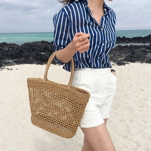 Handmade woven straw tote bag for beach vacations with natural hollow mesh texture