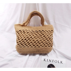 Detail shot of the woven cotton beach bag with hollow mesh pattern on white linen