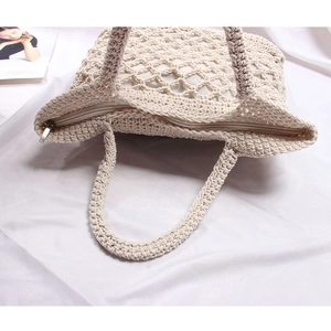 Detail of cream woven cotton handbag featuring secure zipper closure and hollow mesh pattern