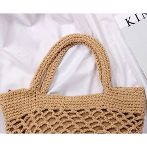 Close-up of thick woven handles and hollow mesh texture on a straw tote bag
