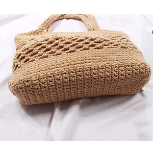 Detailed top view of handmade hollow straw beach bag with woven handles on white fabric
