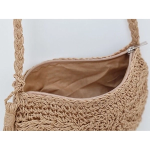 Detail view of straw woven bag showing metal zipper closure and interior lining fabric