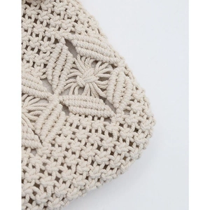 Close-up of beige handmade crochet bag showing floral hollow patterns and cotton lining