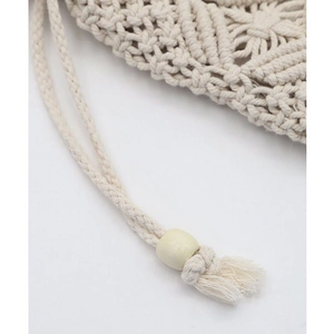 Detail of woven cotton bag with hollow geometric patterns, wooden beads, and tassels
