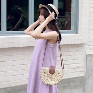 Detail of a handmade semi-circle straw bag with brown leather flap on a summer outfit