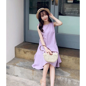 Detail of a purple sleeveless A-line linen dress with a semi-round straw crossbody bag