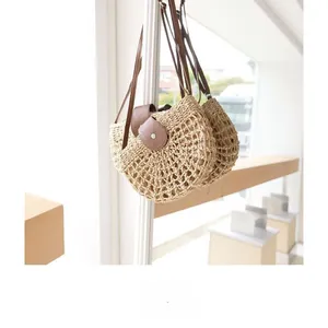 Detail of hollow-out straw handbag with brown leather flap and silver buckle closure