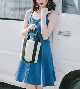 Detail of straw woven bucket bag with black canvas straps and casual summer outfit