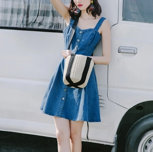 Detail of a straw bucket bag paired with a denim dress for a summer beach vacation style