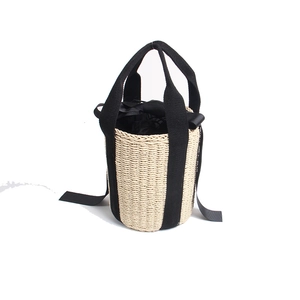 Detail of straw bucket bag with black canvas handle and drawstring closure