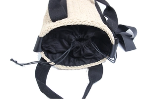 Top view of straw bucket bag featuring black fabric handles and a drawstring inner pouch