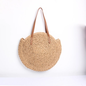 Detail of round straw bag showing spiral woven texture and brown leather handles