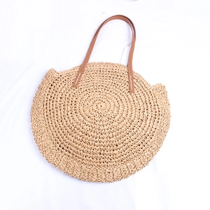 Detail of round straw bag with cat ear design and brown leather handles for beach