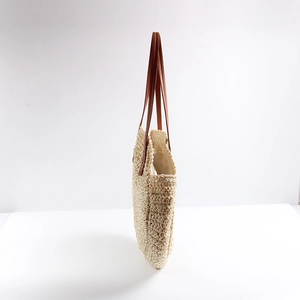 Minimalist beige woven straw shoulder bag with dark brown leather straps for beach vacation
