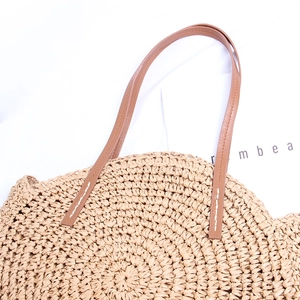 Macro detail of the woven spiral straw pattern and brown faux leather handle stitching