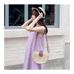 Handmade hollow straw crossbody bag paired with purple dress and flat top woven sun hat