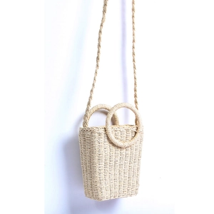 Detailed close-up of woven straw texture and circular handles on a beige bucket bag