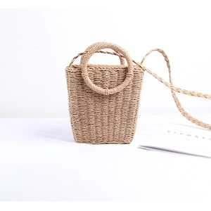 Detail of hand-woven straw crossbody bag with round handles and natural fiber texture