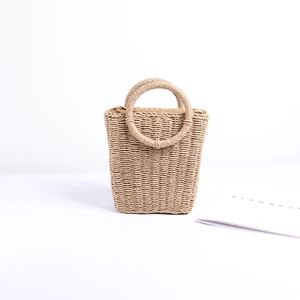 Detail of woven straw bag showing a round handle and natural texture on white background