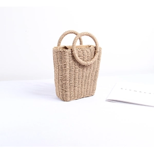 Detailed view of handmade woven straw bag with unique circular handles for summer beach