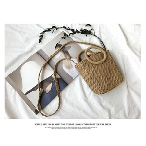 Top view of handmade straw bucket bag with round handles on white fabric background