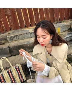 Detail of a large striped straw tote bag with textured knit fabric in a travel setting