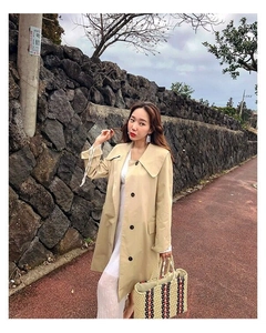 Outdoor street style shot of a woman holding a large striped woven straw beach handbag