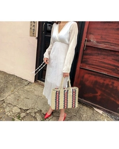 Detailed view of a striped straw tote bag paired with a white V-neck maxi summer dress