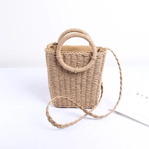Handwoven straw bucket bag with round handles and long strap for beach vacation