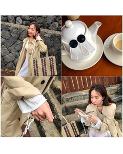Detail of a large striped straw tote bag paired with a stylish beige trench coat