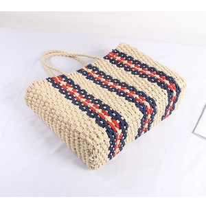 Detail of nautical striped straw tote bag showing navy and red woven texture on cream base