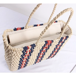 Detail of hand-woven straw tote with red-blue stripe accent and durable rope handles