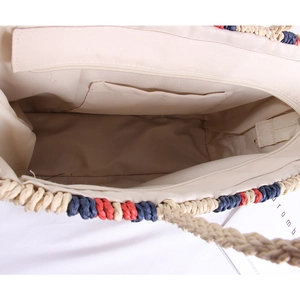 Detail view of woven straw tote bag featuring fabric lining, zipper closure, and inner pocket
