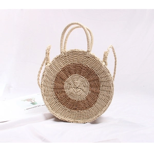 Detail of handwoven straw bag showing round two-tone design and sturdy handles