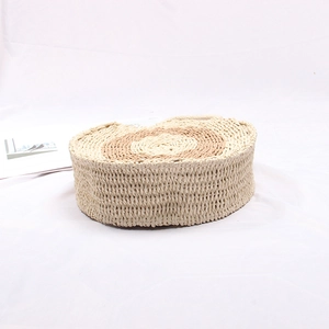 Detail of handwoven round straw bag with beige spiral texture on white tablecloth