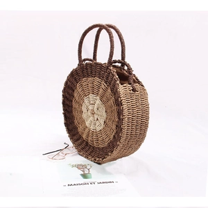 Detail of round straw bag with triple-tone brown woven layers and circular handles
