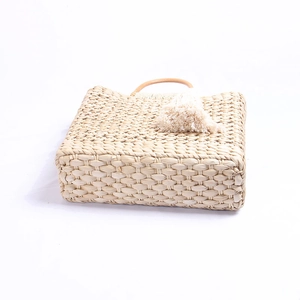 Sac à main en paille beige bohème avec anses rondes en bois et glands sur fond blanc