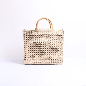 Détail macro du sac en paille tressé à la main avec poignées rondes en bois lisses
