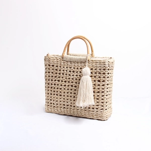 Détail du sac cabas en paille tissé ajouré avec poignées en bois et glands bohèmes