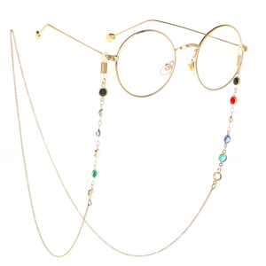 Detail of a retro gold round glass frame with colorful beaded chain on white background