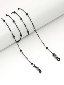 Detail of black beaded metal eyewear chain wrapped around a white cylinder prop