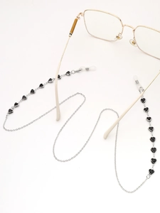 Détail d'une chaîne de lunettes argentée avec charms cœurs noirs et attaches en gomme