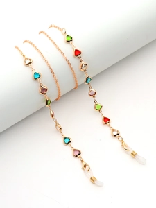 Détail de chaîne de lunettes dorée avec coeurs en cristal coloré et boucles silicone