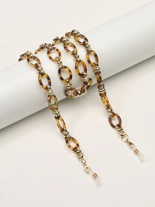 Détail de la chaîne à lunettes en acrylique écaillé avec anneaux dorés et embouts