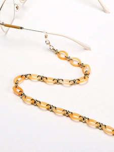 Détail de la chaîne pour lunettes en acrylique ambre et maillons métalliques dorés