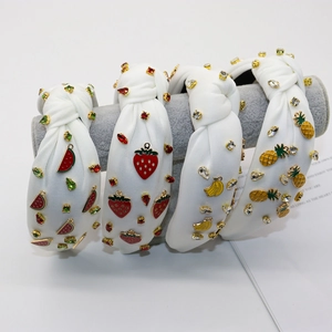 Detail of four white knotted headbands with crystal-studded fruit charms and enamel accents