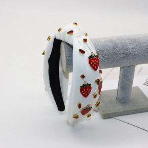 Detail of white knotted headband with red strawberry charms and sparkling rhinestones