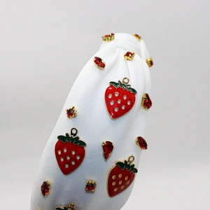 Detail of white knotted headband with red enamel strawberries and ruby rhinestones
